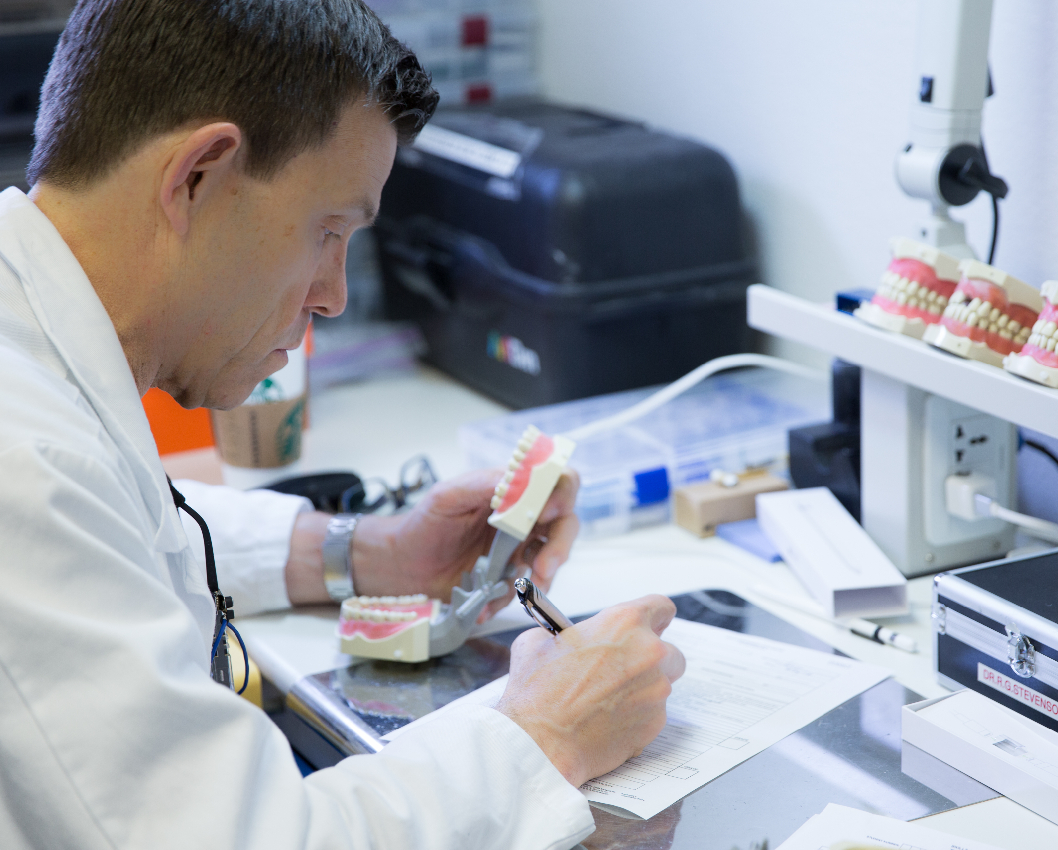 Dr. Richard Stevenson evaluating a typodont during a bench exam mock assessment